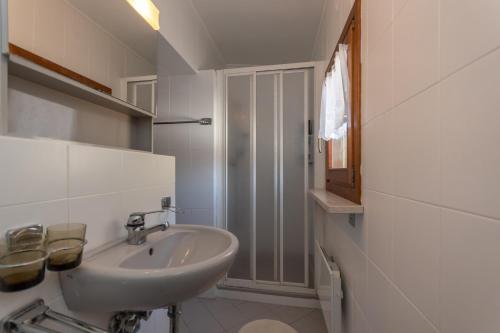 a white bathroom with a sink and a shower at Casa Narciso in Rocca Pietore