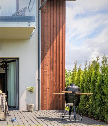 a grill on a deck next to a house at GENIO 7 apartamentai in Palanga