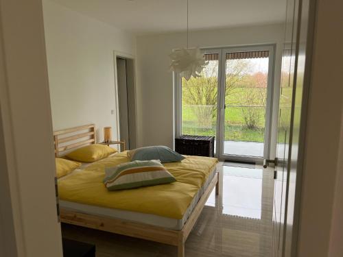 1 dormitorio con 1 cama con sábanas amarillas y ventana en Résidence du Golf Eselborn en Eselborn