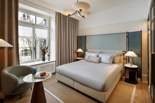 a bedroom with a bed and a chair and a table at Small Luxury Hotel Ambassador Zurich in Zürich