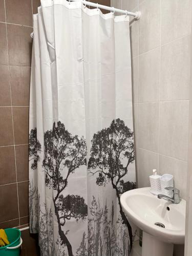 a bathroom with a shower curtain with trees on it at Promenad Burabay 45P in Borovoye