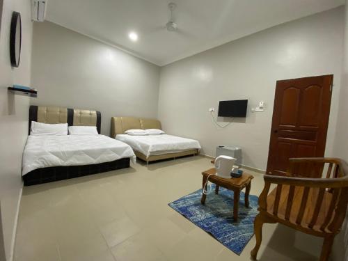 Habitación con 2 camas, silla y TV. en Sasuka Guesthouse (Muslim Sahaja), en Marang