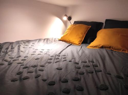 une chambre avec un lit avec des oreillers jaunes dans l'établissement Studio atypique centre Rouen, à Rouen