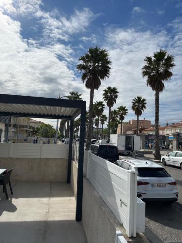 a car parked in a parking lot with palm trees at Petite maison à 100m de la plage in Marseillan
