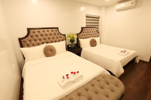 2 Betten in einem Hotelzimmer mit Futternäpfe drauf in der Unterkunft Royal Văn Phú Hotel in Hanoi