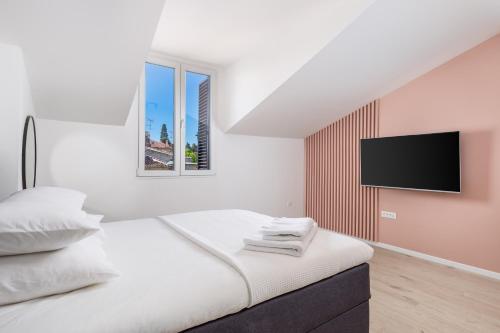 a white bedroom with a bed with a flat screen tv at Apartment Pearl, Opatija center in Opatija
