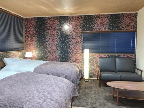 ein Hotelzimmer mit 2 Betten, einem Stuhl und einem Tisch in der Unterkunft Kyoto Ryokan Gion Sano in Kyoto