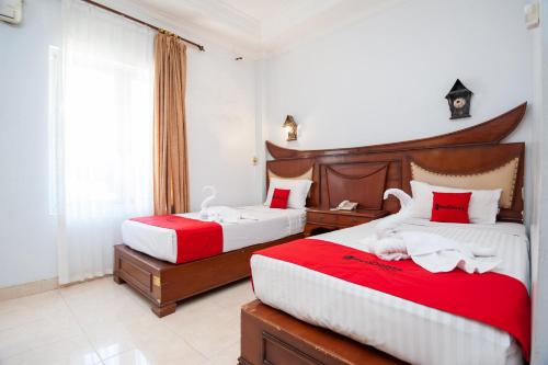 1 dormitorio con 2 camas con sábanas rojas y blancas en RedDoorz Syariah near RS Yos Sudarso Padang en Padang