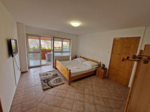 - une chambre avec un lit et une porte donnant sur un balcon dans l'établissement Simple Apartman, à Siófok