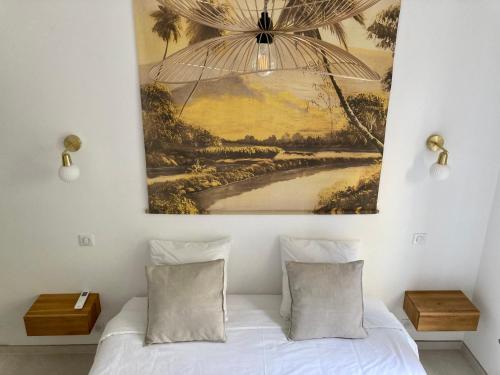 - une chambre avec un tableau au-dessus d'un lit et 2 oreillers dans l'établissement Cannes - L'Oustaou, à Cannes