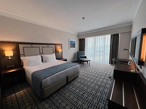 a hotel room with a bed and a flat screen tv at Ramada Plaza by Wyndham Rize in Rize