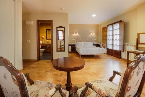 ein Wohnzimmer mit einem Tisch und ein Schlafzimmer in der Unterkunft Hotel Rural Casona de Cefontes in Cefontes