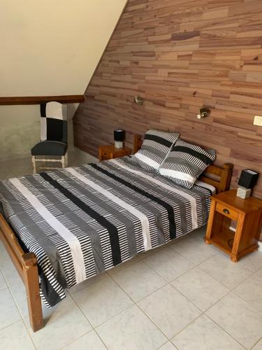 - un grand lit dans une chambre dotée d'un mur en bois dans l'établissement Bergerie rénovée au coeur des Pyrénées, à Campan