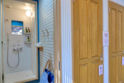 a bathroom with a shower and a wooden door at Retreat Camp Mahoroba in Fujikawaguchiko