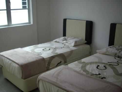 two twin beds in a room with a mirror at Greenleaf Angsana Homestay in Jerantut