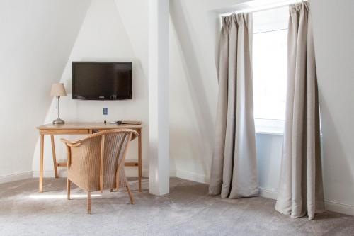 Zimmer mit einem Schreibtisch, einem TV und einem Fenster in der Unterkunft Hotel Trabener Hof in Traben-Trarbach