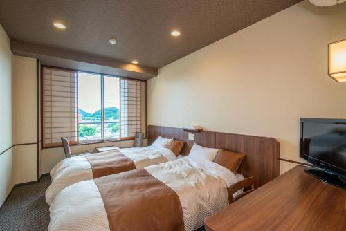 a bedroom with two beds and a flat screen tv at New Hakkeien in Izunokuni