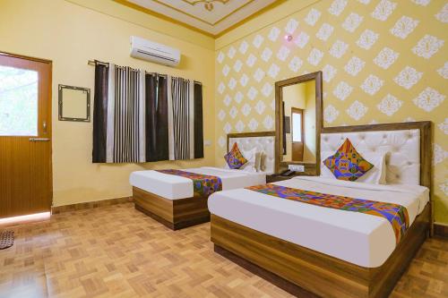 a hotel room with two beds and a mirror at FabHotel Shivam Palace in Varanasi