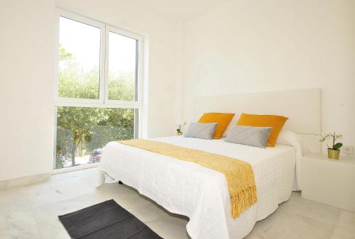 a white bedroom with a large bed and a window at Colonia Sea Holiday in Colonia Sant Jordi