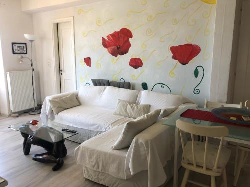 a living room with a white couch and red flowers on the wall at The Best Town View in Mýkonos City