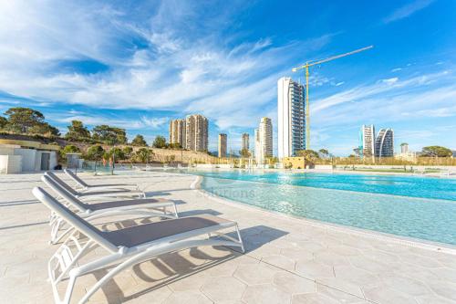 - une rangée de chaises longues à côté de la piscine dans l'établissement Intempo Sky Apartments 096, à Benidorm