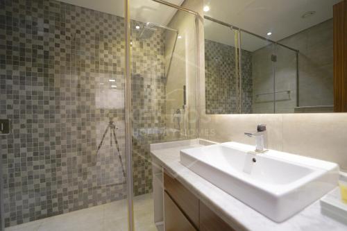 a bathroom with a sink and a glass shower at KeyHost - Cozy 1BR Apartment Near Five Hotel - JVC - KG40 in Dubai