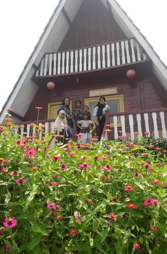 a group of people standing outside of a house with flowers at Monthong twbm Rumpin in Sawah