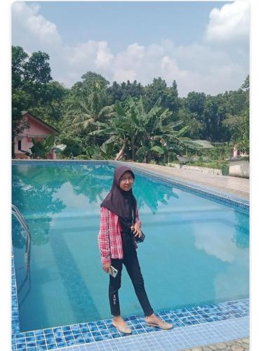a woman standing next to a swimming pool at Monthong twbm Rumpin in Sawah