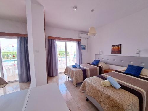 a hotel room with three beds and a balcony at Florence Hotel Apartments in Ayia Napa
