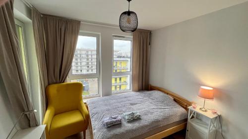 sypialnia z żółtym krzesłem i oknem w obiekcie Granata Apartments w mieście Lublin