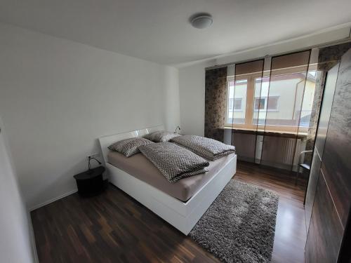 ein weißes Schlafzimmer mit einem Bett und einem Fenster in der Unterkunft Ferienwohnung Braunshardt in Weiterstadt