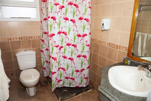 a bathroom with a toilet and a shower curtain with red flowers at Apartment Sharm in Sharm El Sheikh