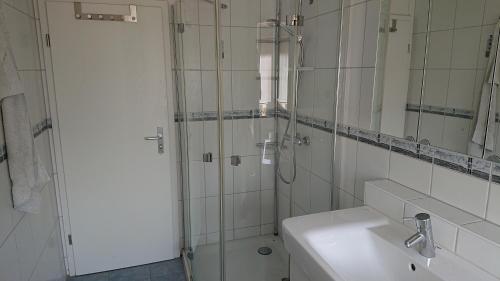 een badkamer met een douche, een wastafel en een spiegel bij Apartment Ferienwohnung Vogt in Sinzheim