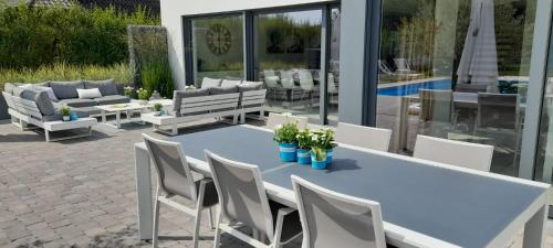 a patio with a white table and chairs at Villa Blue Garden B&B Vlaamse Ardennen nabij Pairi Daiza in Geraardsbergen