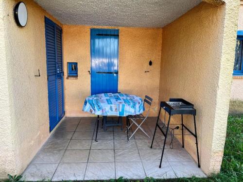 une table et des chaises sur une terrasse avec une porte bleue dans l'établissement Charmant appartement en résidence de vacances avec piscine, à Argelès-sur-Mer