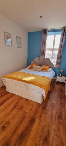 a bedroom with a large bed with a wooden floor at Modern and spacious Swansea centre apartment in Swansea