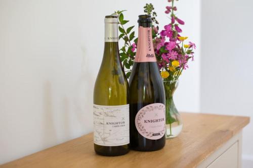 two bottles of wine sitting next to a vase of flowers at Home from Home self catering for 2 in St Austell