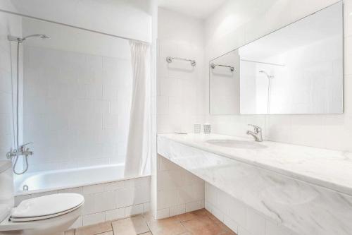 a white bathroom with a toilet and a sink at Villa Tamarells Ullastres in Punta Prima