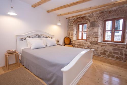 una camera con un letto bianco e un muro di mattoni di Casa Milina a Šibenik