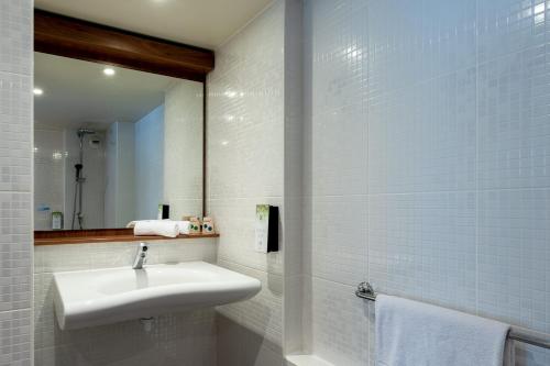 Baño blanco con lavabo y espejo en Campanile Rouen Sud - Zénith - Parc Expo en Saint-Étienne-du-Rouvray