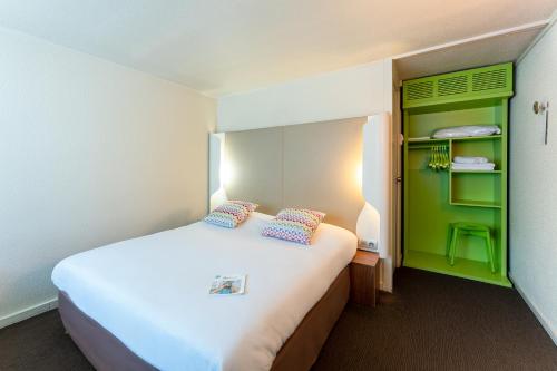 サン・テティエンヌ・デュ・ルヴレにあるCampanile Rouen Sud - Zénith - Parc Expoのベッドと緑のキャビネットが備わるホテルルームです。