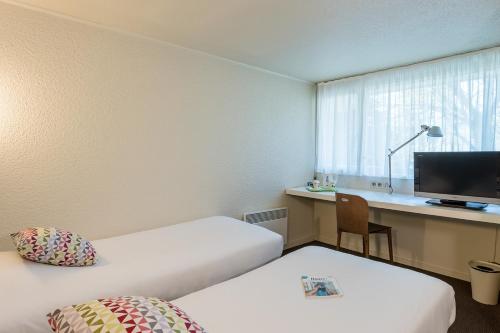 a room with two beds and a desk with a computer at Campanile Rouen Sud - Zénith - Parc Expo in Saint-Étienne-du-Rouvray