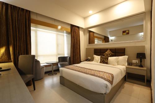 a hotel room with a large bed and a chair at Aristocrat Hotel in Kolkata