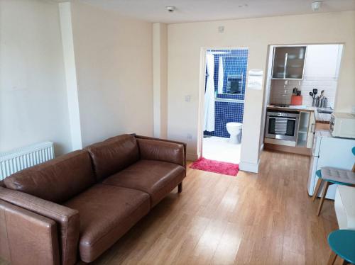 ein Wohnzimmer mit einem braunen Sofa und einer Küche in der Unterkunft Self-contained private apartment Unit 1 in London