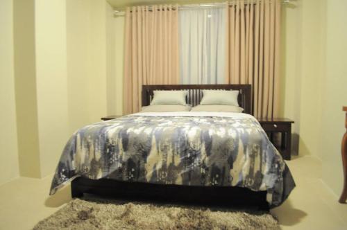 a bedroom with a bed with a black and white comforter at SERIN WEST TAGAYTAY-Spacious & Comfy 2BR Unit with Parking and Balcony in Tagaytay