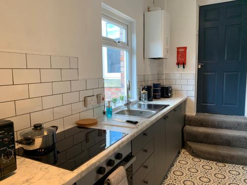 a kitchen with a sink and a blue door at Windsor 4 - Spacious beautiful 4 bdrm maisonette nr Ncle free wifi free parking in Gateshead