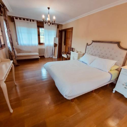 a bedroom with a large white bed and wooden floors at Caserio Kamirune in Laukiz