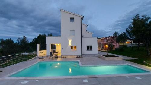 a villa with a swimming pool in front of a house at Villa Mare in Ližnjan