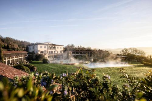 a garden with a building in the background at Adler Spa Resort Thermae in Bagno Vignoni