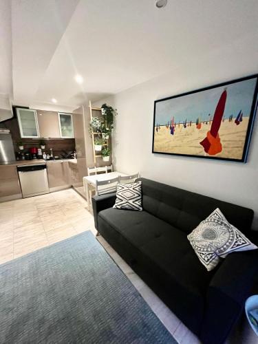 un salon avec un canapé noir et une cuisine dans l'établissement Deauville, maison au coeur de la ville, à Deauville